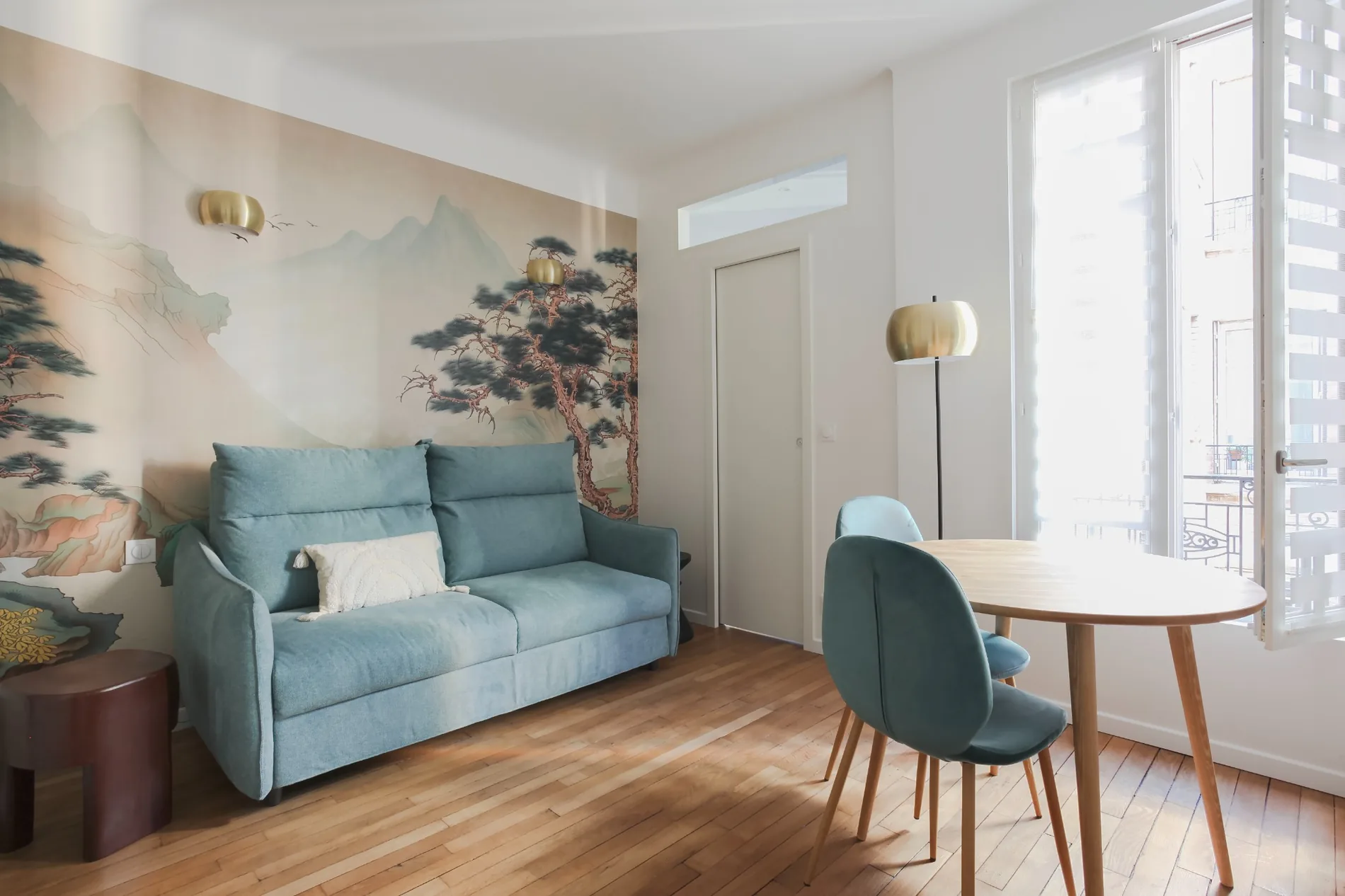 Photographie du séjour, mobilier bleu et papier peint paysager