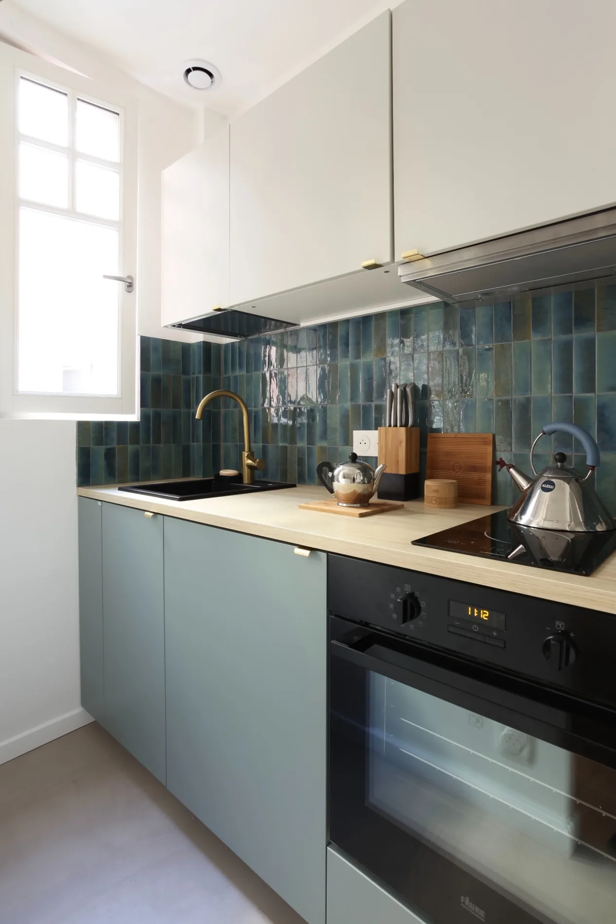 Photographie de la cuisine aux carreaux bleu-vert et façades claires