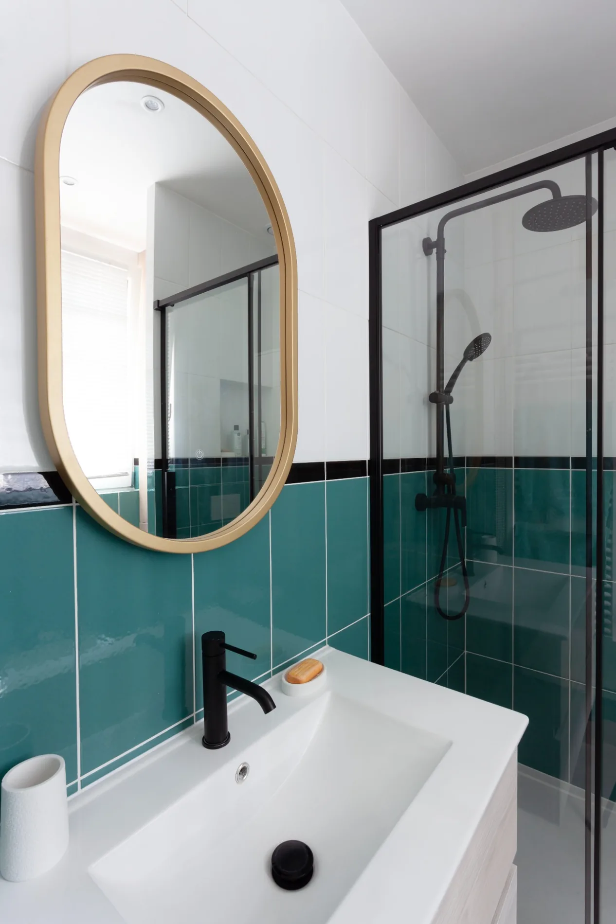 Salle de bains lumineuse avec miroir arrondi et carrelage turquoise