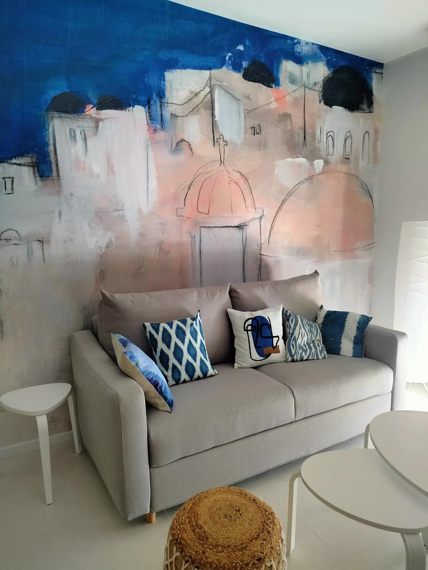 Canapé clair devant une peinture murale aux accents bleus et roses