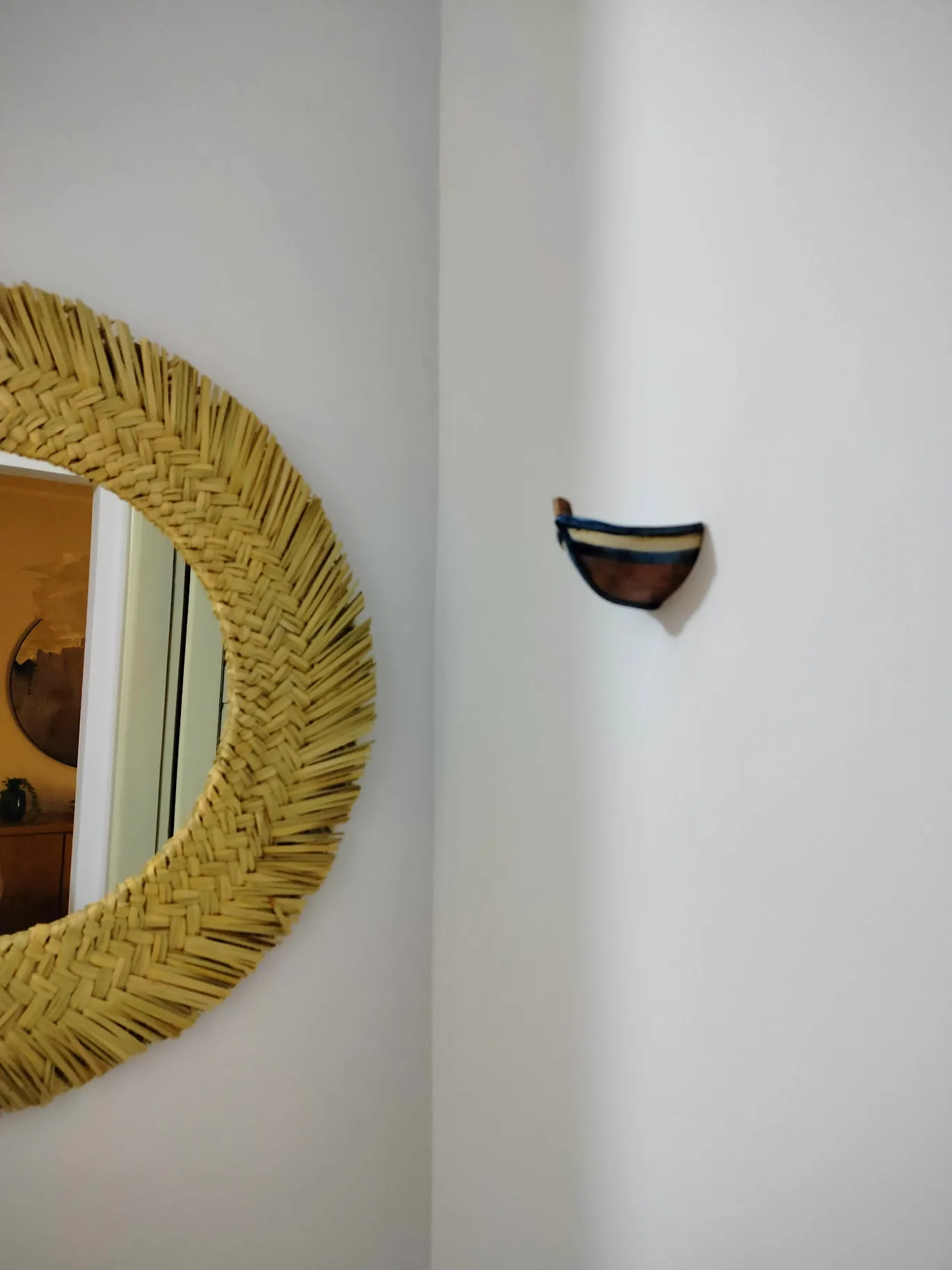 Miroir en fibres tressées sur une paroi blanche
